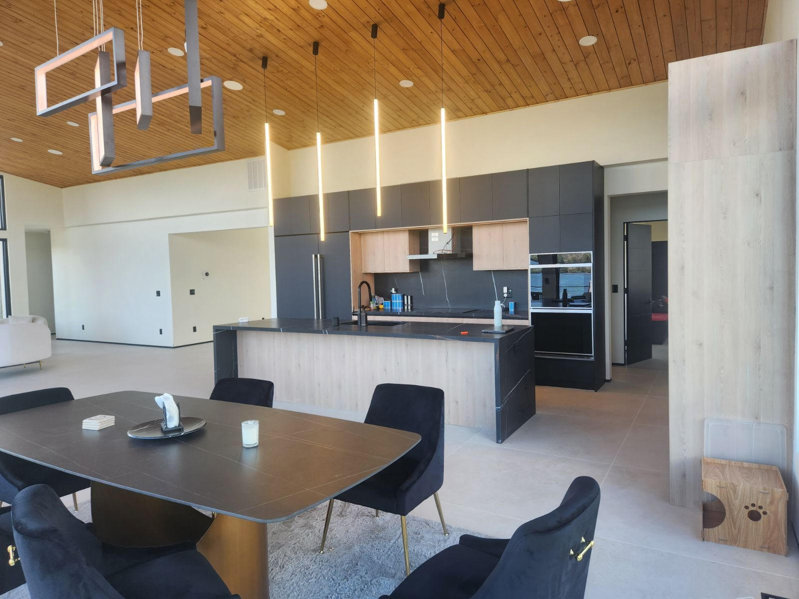 Open-concept kitchen and dining with wood ceiling and designer lighting